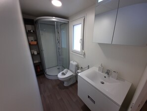 A modern bathroom with a glass shower enclosure, a toilet, and a sink.