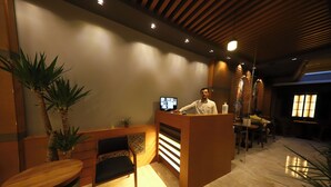 A reception area with a wooden reception desk, a chair, and a television screen. - Ruby Royal Hotel (Istanbul)