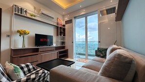 A modern living room with a flat-screen TV, a sofa, a coffee table, and a bookshelf. - Paragon Suite By Antlerzone (Johor Bahru)