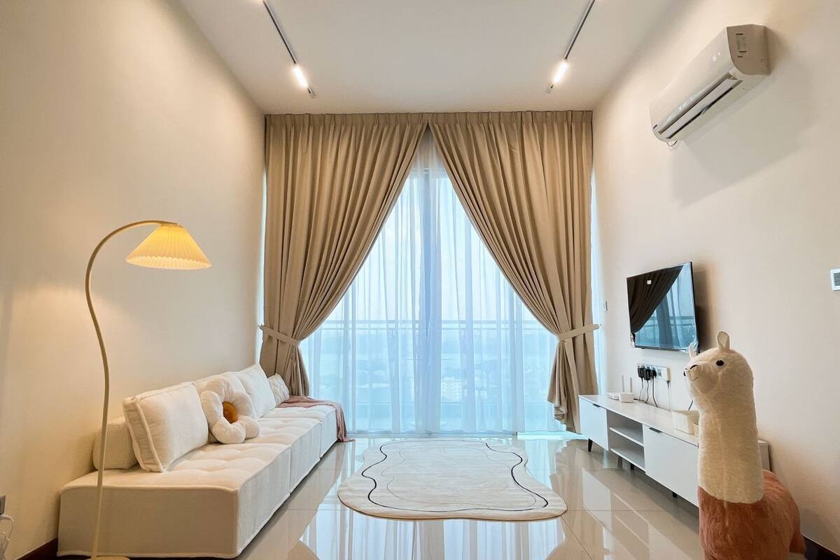 A modern living room with a sofa, a flat-screen TV, an air conditioner, and a large window with curtains.