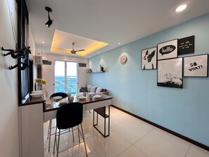 Un espace de restauration moderne offrant une vue sur le paysage urbain, doté d’un ventilateur de plafond et agrémenté d’œuvres d’art murales.