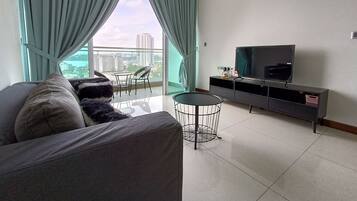A modern living room with a grey sofa, a small round table, and a TV on a black stand.