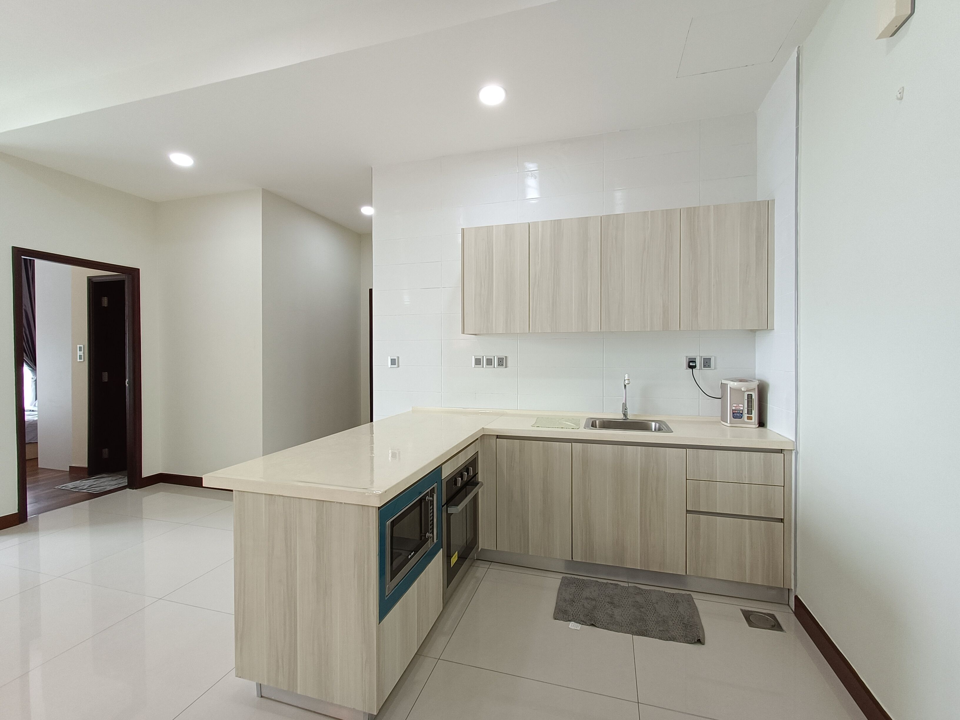 A modern kitchen with a built-in oven, a sink, and wooden cabinets.