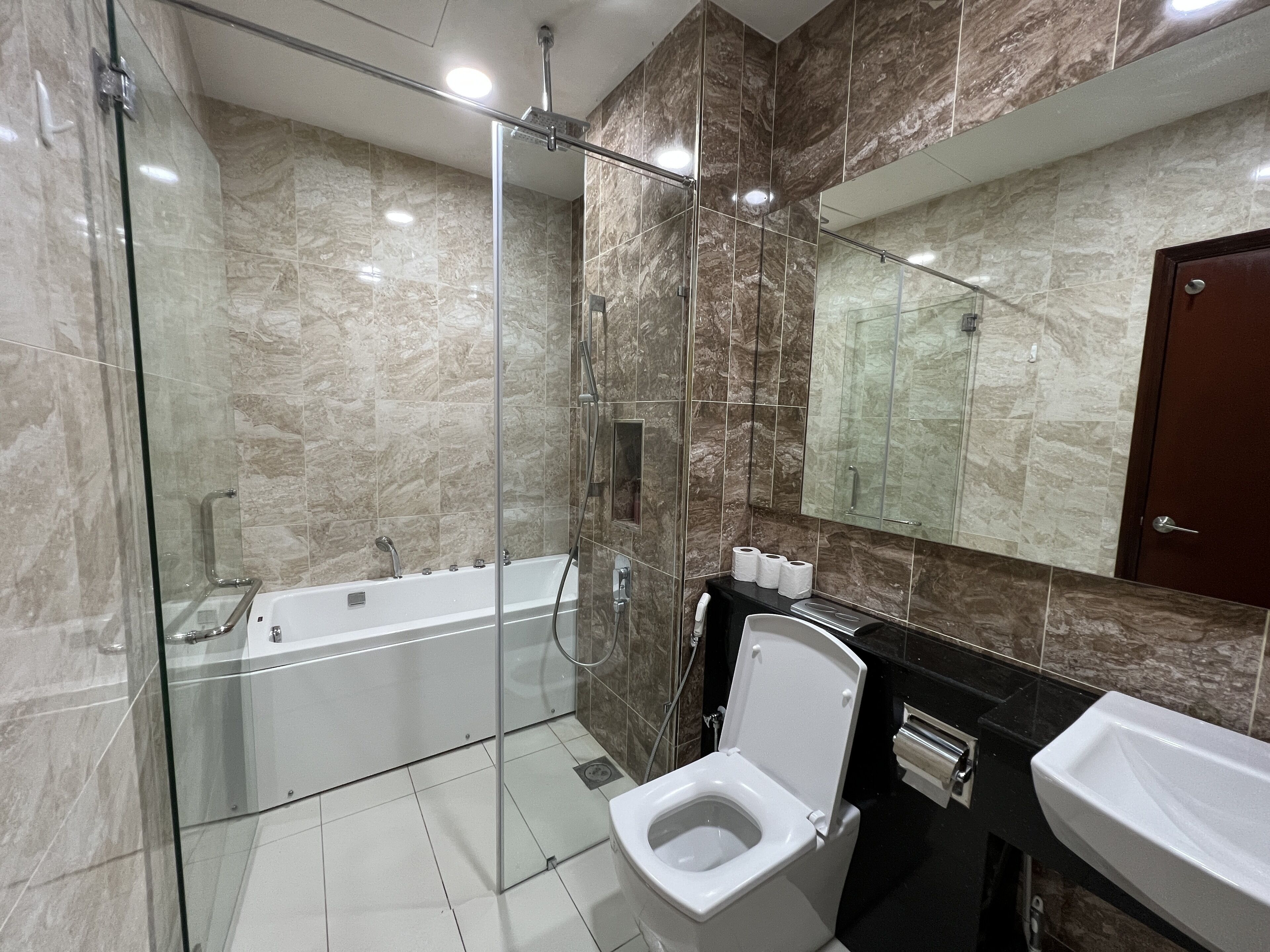 Un baño moderno con ducha de vidrio, bañera blanca y un inodoro.
