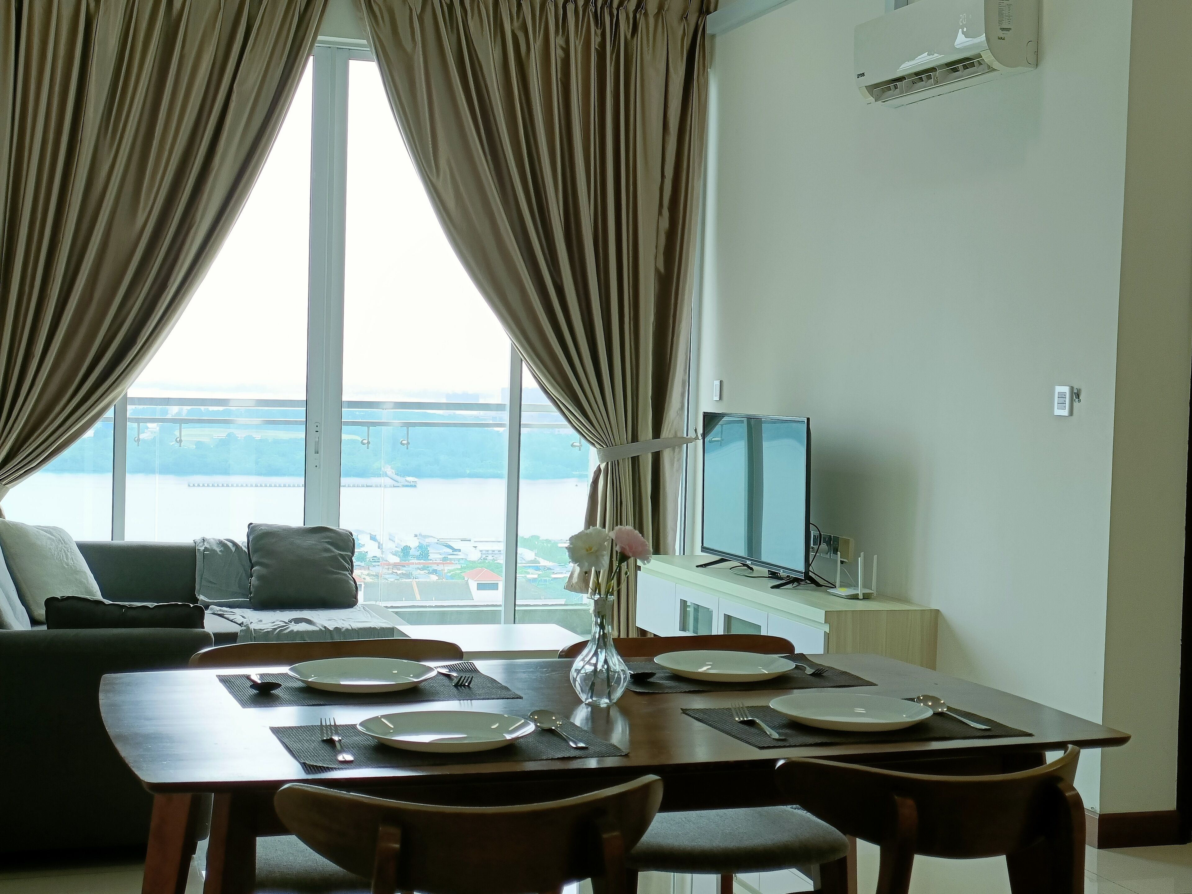 A dining area with a table set for two, a sofa, and a TV in the background.