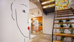 A modern interior with a staircase, a glass partition, and a kitchen area visible through the partition. - Lukanda Hospec Olehousing (Seville)