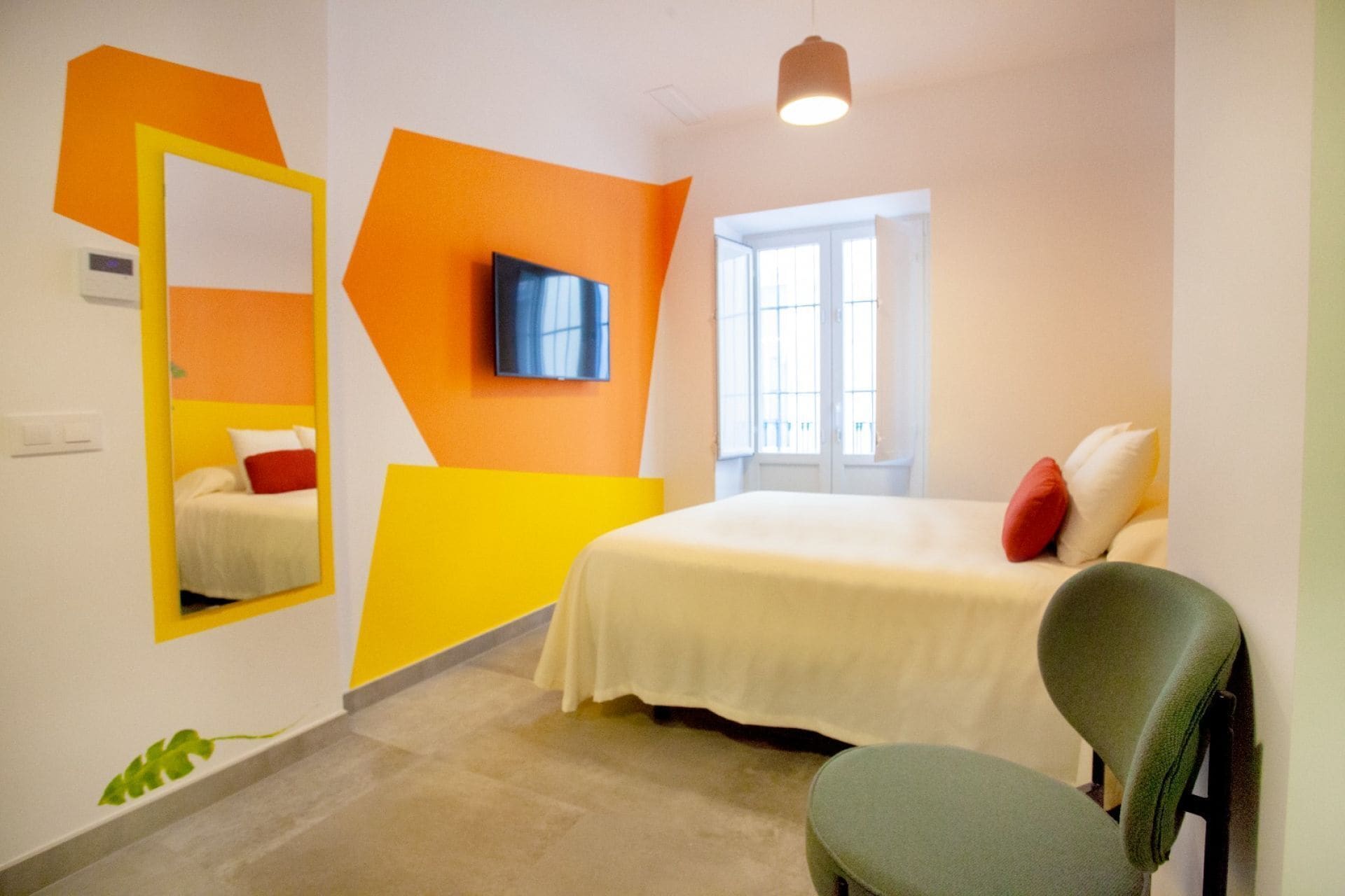 Una habitación de hotel moderna con cama, una silla, un televisor y una ventana.
