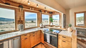 A kitchen with wooden cabinets, a stove, and large windows overlooking a scenic landscape.