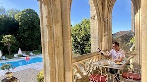 A stone archway overlooking a pool area with outdoor seating and a dog nearby. - Fairytale Chateau with pool surrounded by vineyard and parc (Blaye)