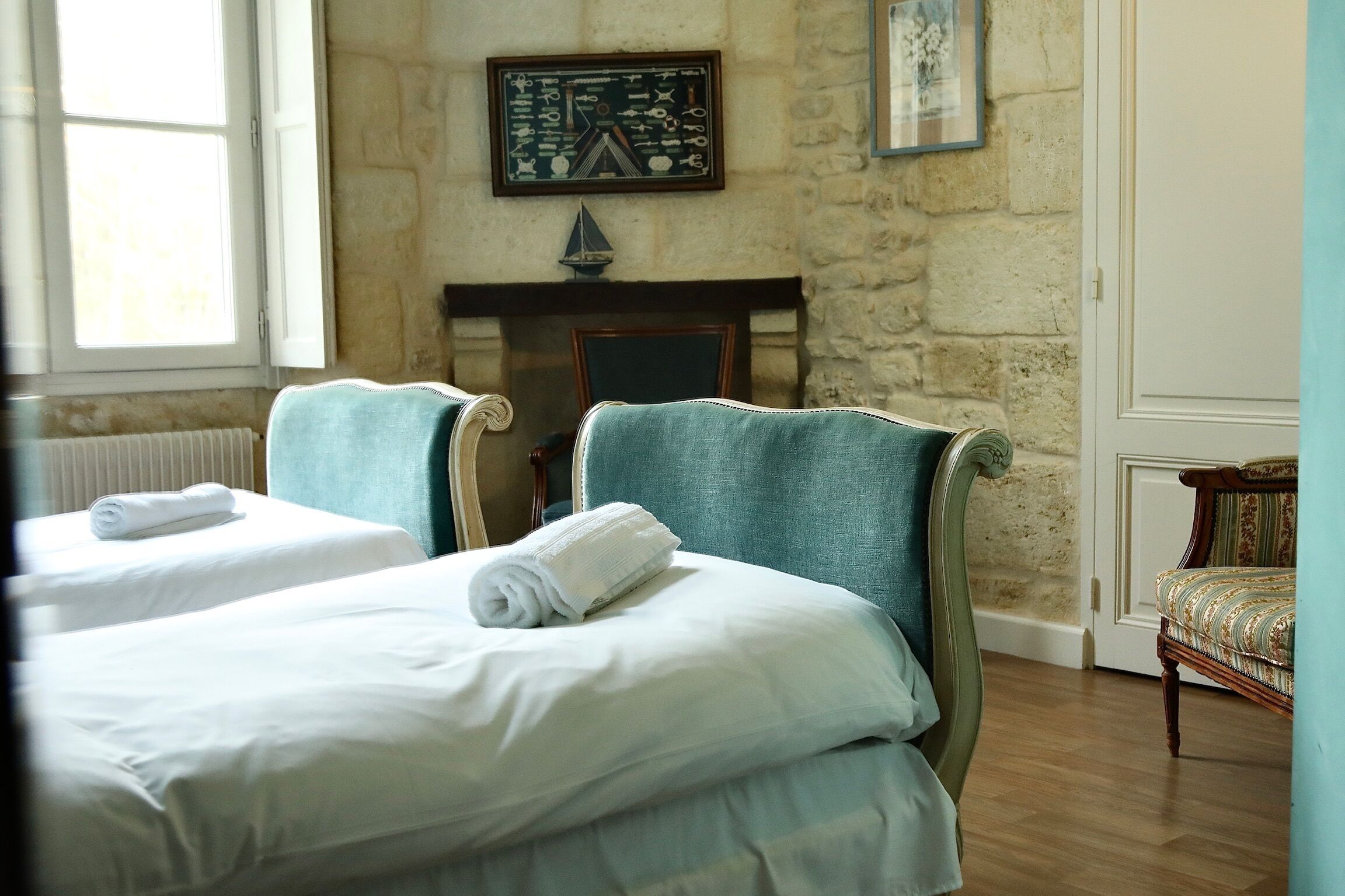 A hotel room with two single beds, a stone wall, a fireplace, and a framed picture above it.
