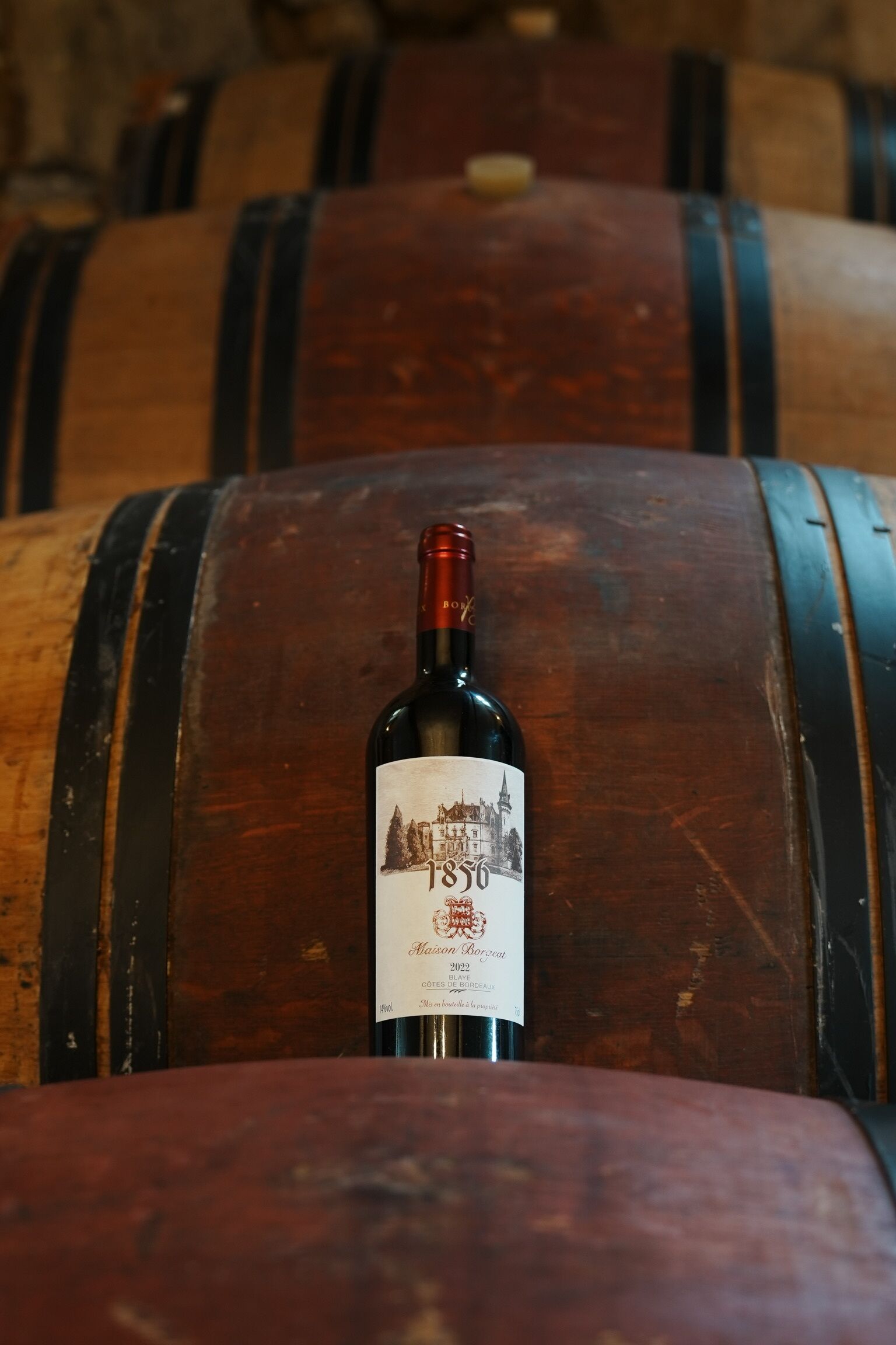 A bottle of wine with a label in a barrel.