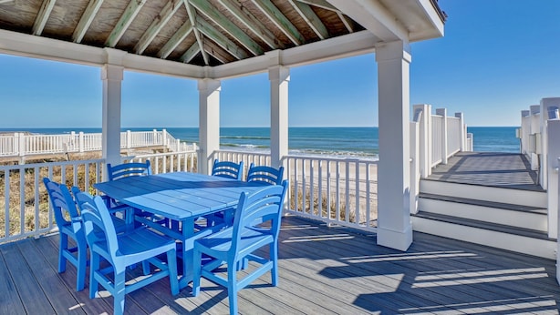 A covered outdoor area with a wooden deck, white railings, and a view of the ocean. - Relax! Oceanfront Home | Pool | Hot Tub | Elevator (North Topsail Beach)