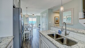 A modern kitchen with granite countertops, stainless steel appliances, and a large island with seating. - Relax! Oceanfront Home | Pool | Hot Tub | Elevator (North Topsail Beach)