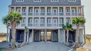 A multi-story building with a symmetrical facade, balconies, and a gated entrance. - Relax! Oceanfront Home | Pool | Hot Tub | Elevator (North Topsail Beach)