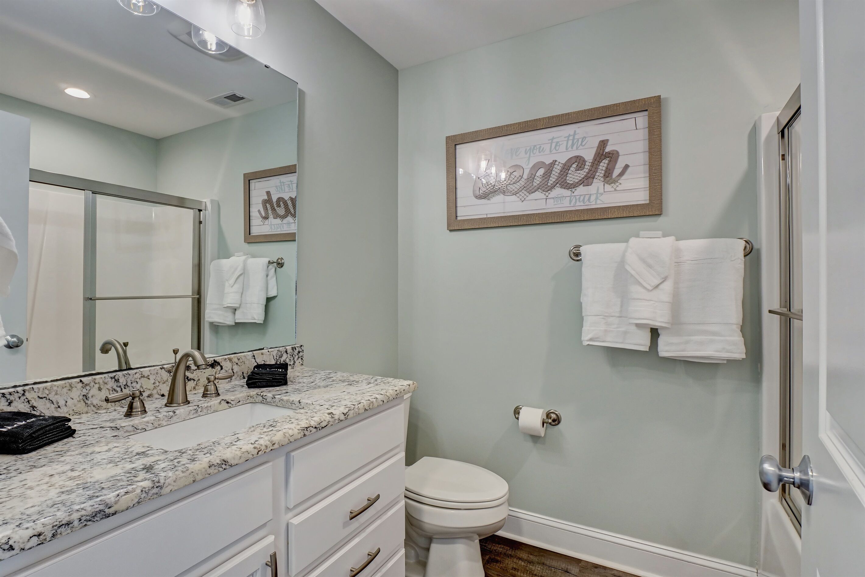 A bathroom with a marble sink, a toilet, and a framed sign on the wall.