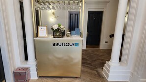 A boutique hotel reception area with a reception desk, framed certificates, and a vase with flowers. - Boutique 50 (Glasgow)