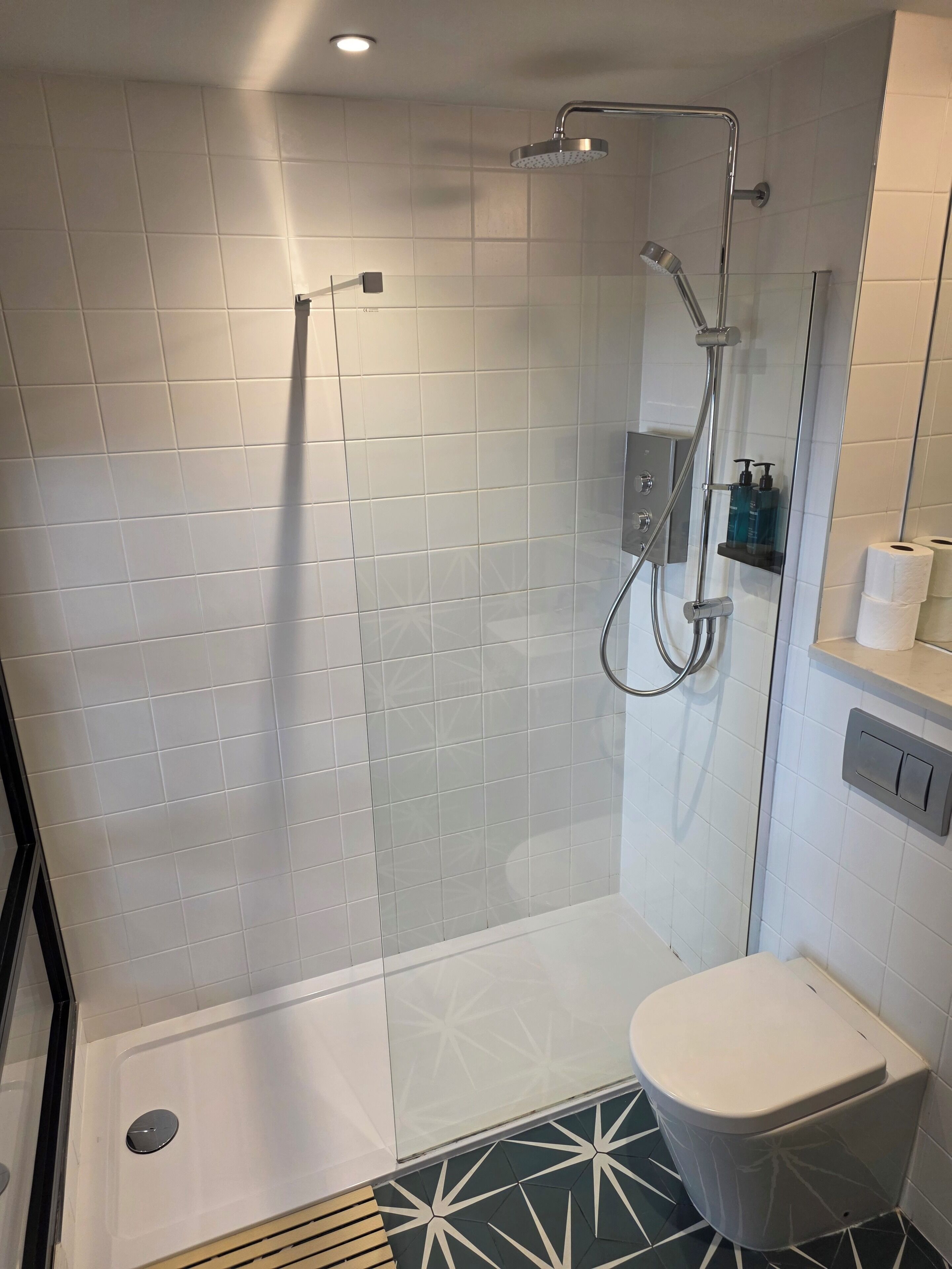 A modern bathroom with a glass-enclosed shower, a toilet, and a sink.