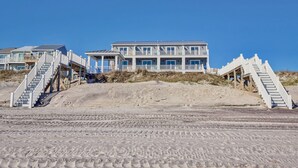 Eine Strandimmobilie mit mehreren Gebäuden, jedes mit einem Balkon und einer Treppe zum Strand.