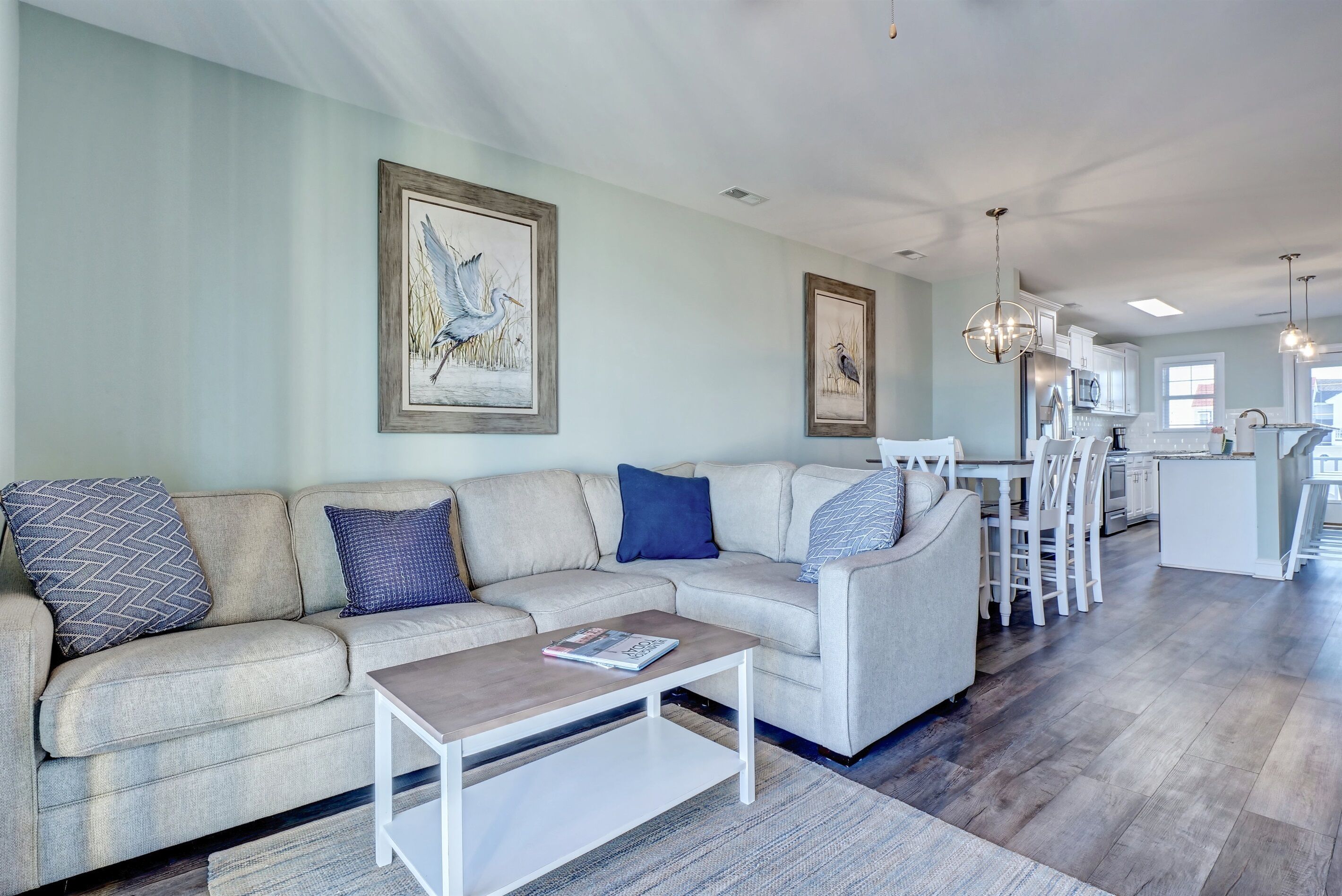 Un salon moderne avec un canapé, une table basse et une œuvre d’art accrochée au mur.