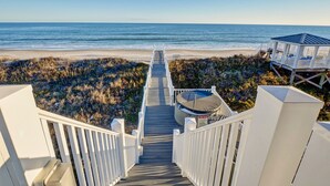 Una escalera de madera que lleva a una playa con una torre de salvavidas y un jacuzzi.