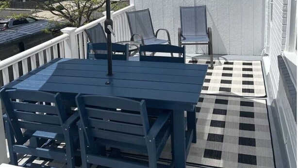 A patio with a table and chairs, an umbrella, and a checkered floor.