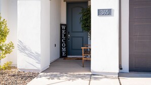 A house entrance with a dark blue door, a welcome sign, and a mailbox with the number 365.