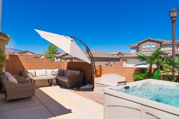 Un espace patio aménagé avec du mobilier d’extérieur, un jacuzzi et un mur en briques.