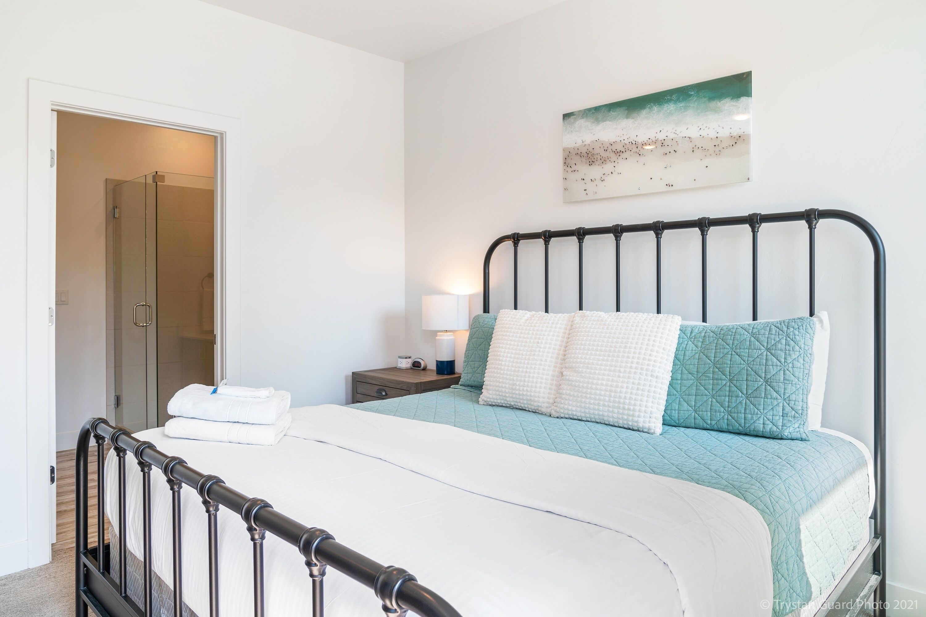 A bedroom with a bed, a nightstand, a lamp, and a painting on the wall.