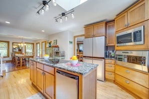 Enjoy cooking in this well-equipped kitchen with a large island, dishwasher, stainless steel refrigerator, and microwave.