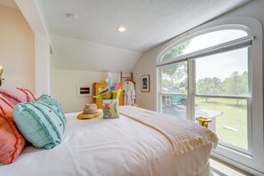 Enjoy a restful stay in this cozy bedroom with a large window offering a view of the outdoors, a comfortable bed, and a bedside table with a lamp.