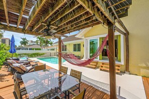 Un espacio al aire libre techado con piscina, sillas de descanso y una hamaca.