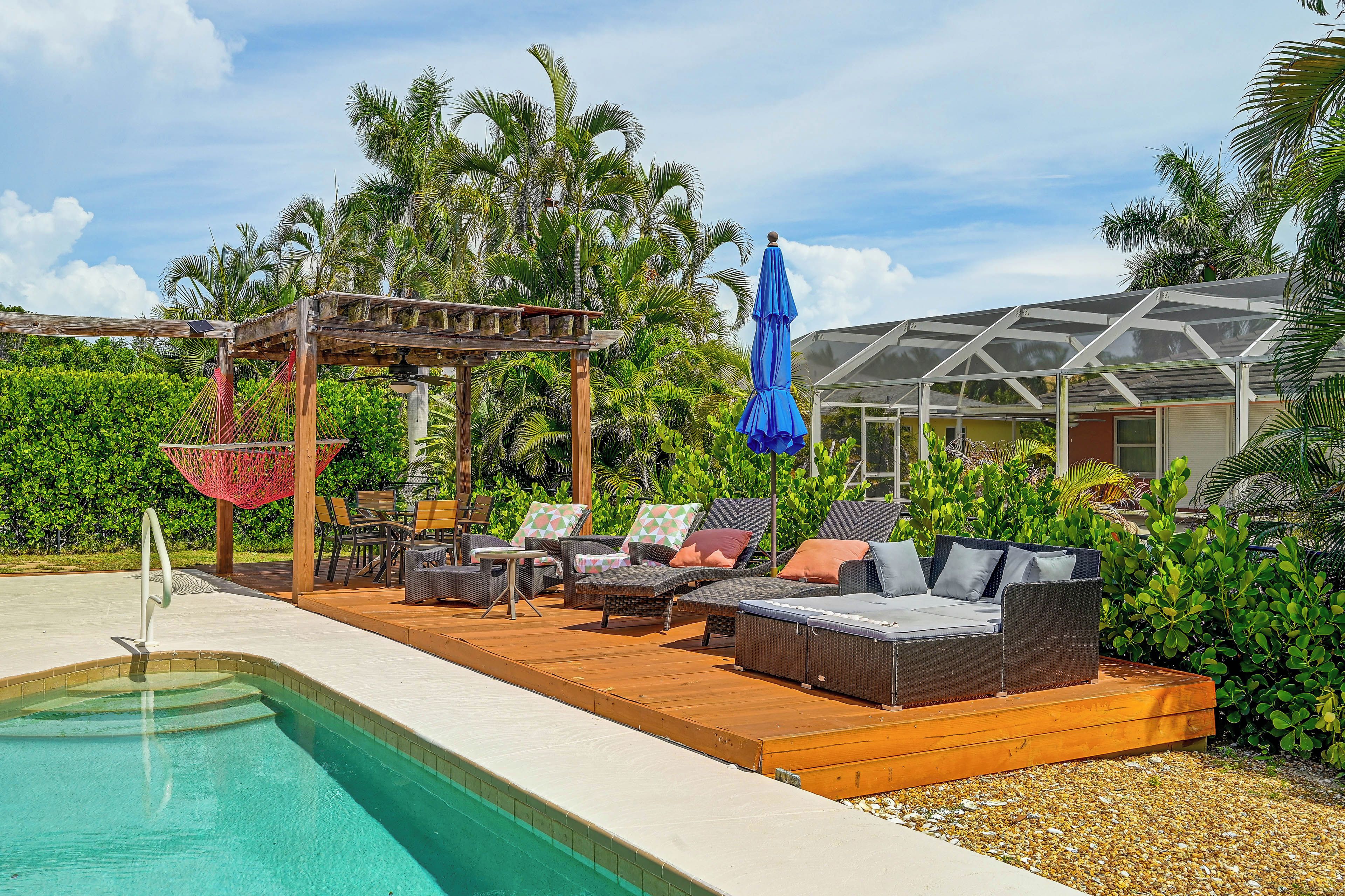 A poolside area with lounge chairs, a hammock, and a covered seating area.