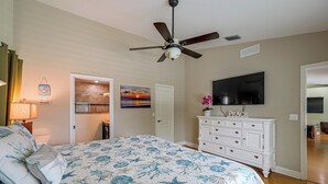 Una camera da letto con un letto, un ventilatore a soffitto, una TV e un comò.