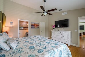 Un dormitorio con cama, ventilador de techo, televisor y cómoda.