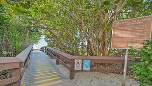 Una passerella in legno che conduce a una spiaggia, con un cartello sulla protezione delle tartarughe marine.