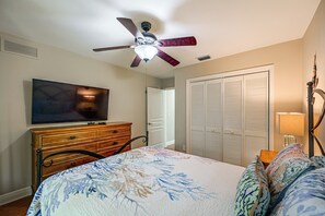 Un dormitorio con una cama, un televisor sobre un tocador, un ventilador de techo y un armario.