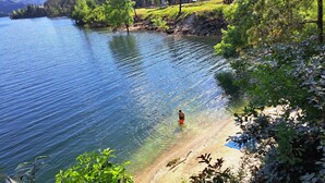 Um lago com águas cristalinas, rodeado por vegetação e uma margem de areia.