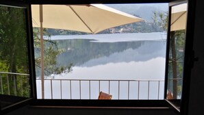 Quarto com vista para um lago e montanhas através de uma janela grande.
