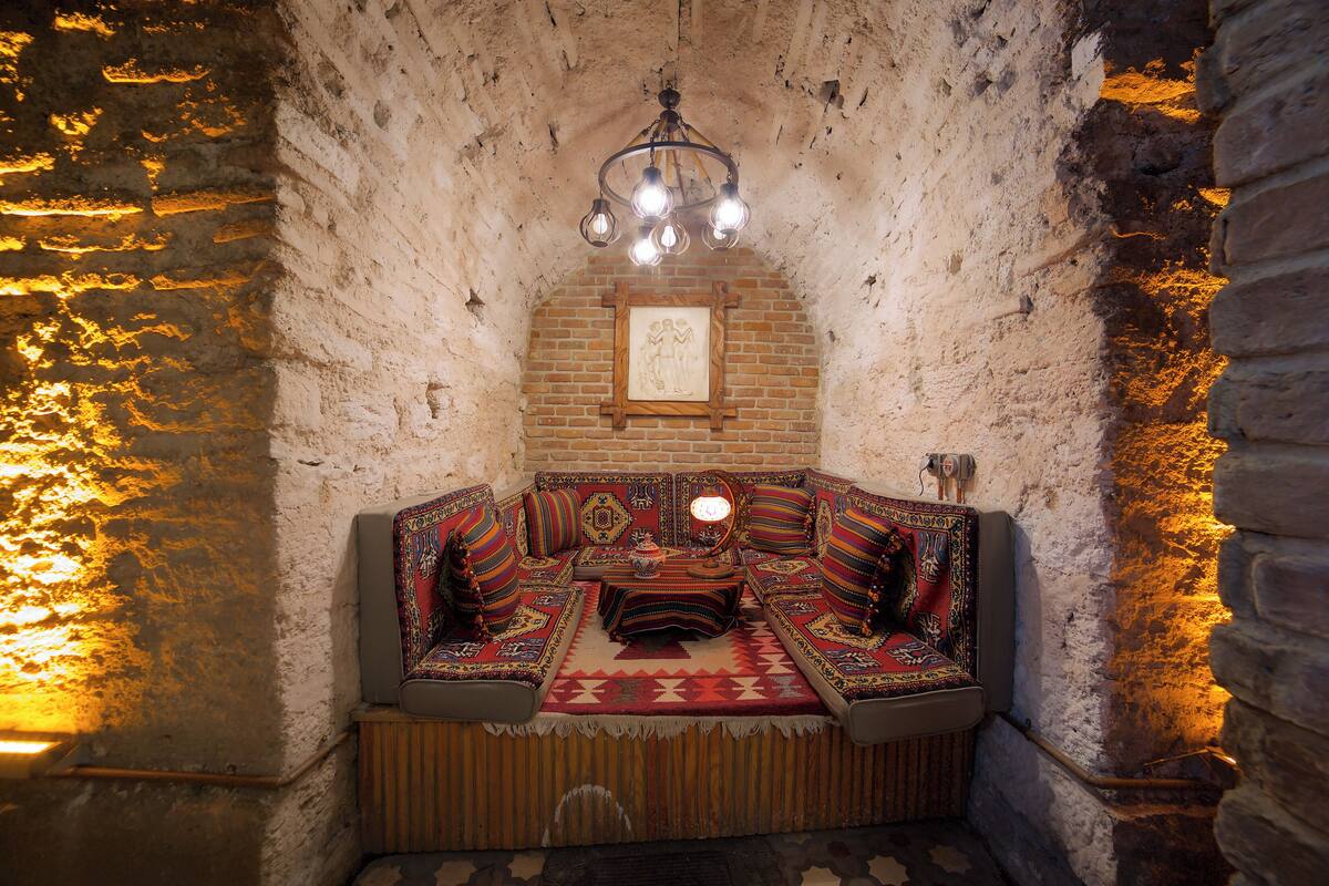 A traditional room with a brick wall, a wooden bench, and a hanging light fixture.