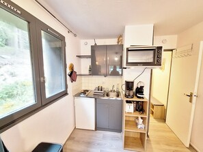 A compact kitchen with a microwave, coffee maker, and a small refrigerator.