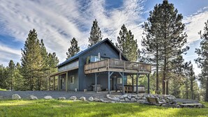 A two-story cabin with a balcony, surrounded by trees and a stone pathway. - 'Peaceful Pines' - Cascade Cabin w/ Hot Tub! (Cascade)