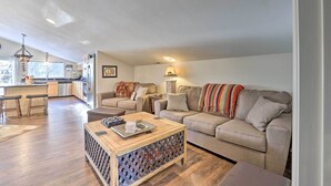 A modern living room with a sofa, coffee table, and a kitchen area in the background. - 'Peaceful Pines' - Cascade Cabin w/ Hot Tub! (Cascade)