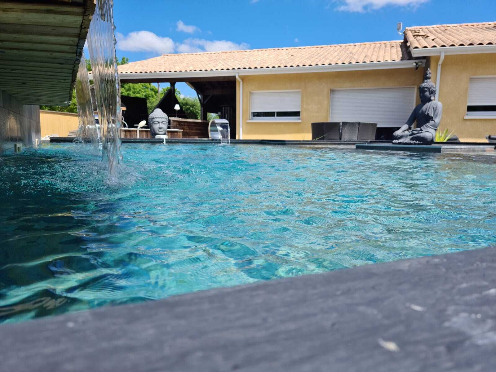 A clear swimming pool with a statue of a seated figure on the right side.