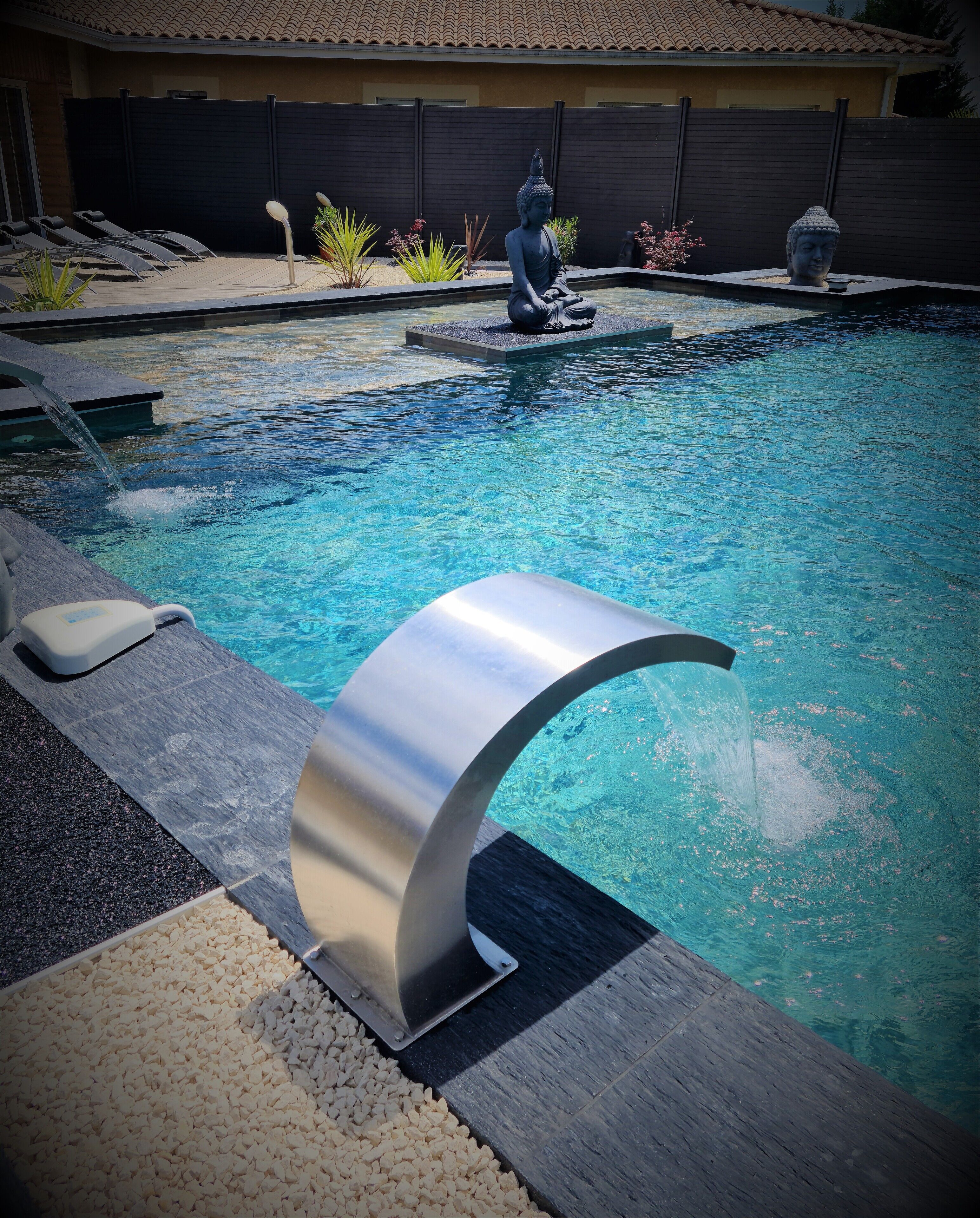 A swimming pool with a modern design, including a curved edge and a statue.
