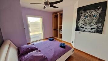 A bedroom with a bed, a ceiling fan, a wardrobe, and a leopard painting.