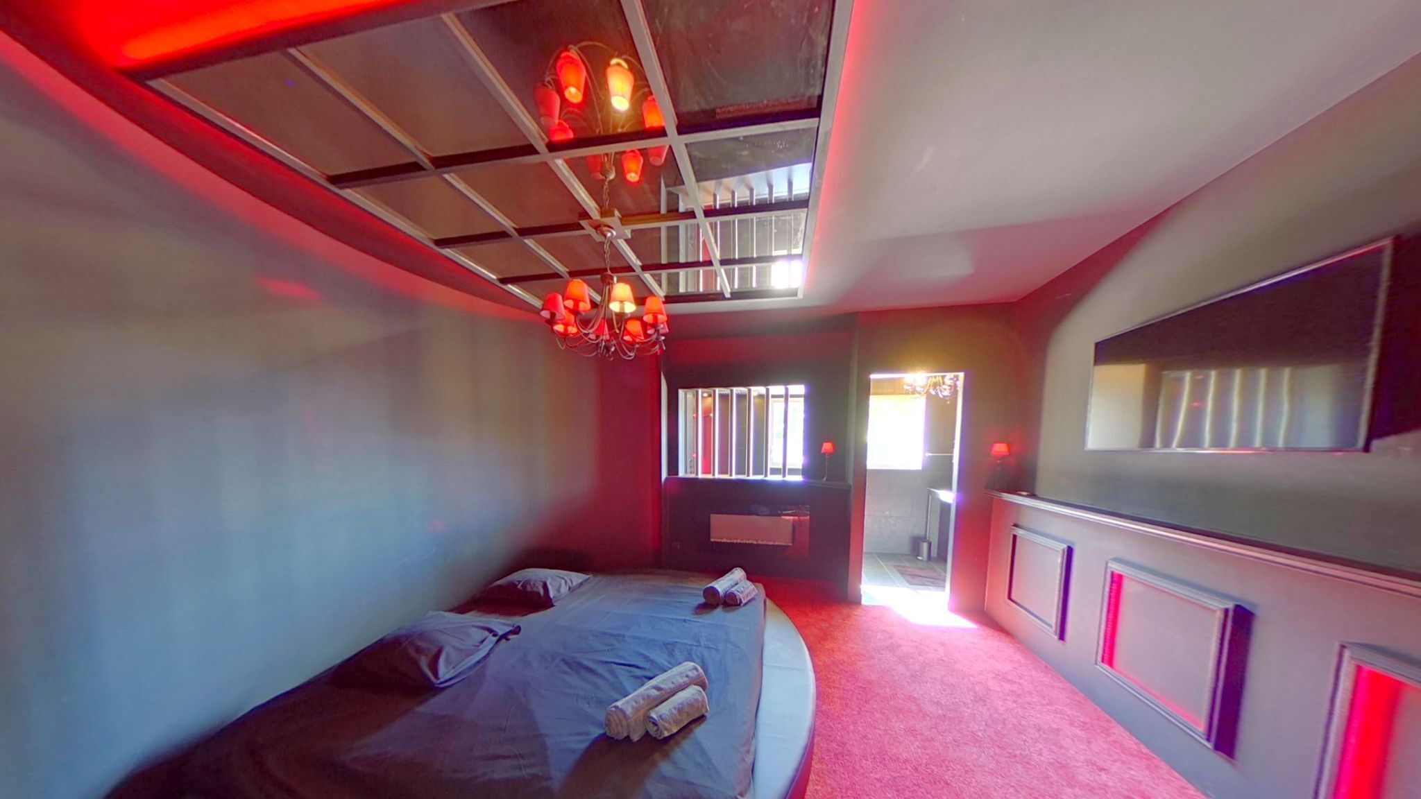 A bedroom with a bed, a mirror, and a ceiling light fixture.