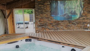 A hot tub area with a stone wall and a mural of a waterfall. - Villa Naeva with swimming pool, Jacuzzi 10 places, Ping pong, plancha and Brasero (Agnac)