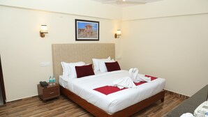 Un cuarto de hotel con una cama grande, piso de madera, dos mesitas de noche y un cuadro enmarcado en la pared.