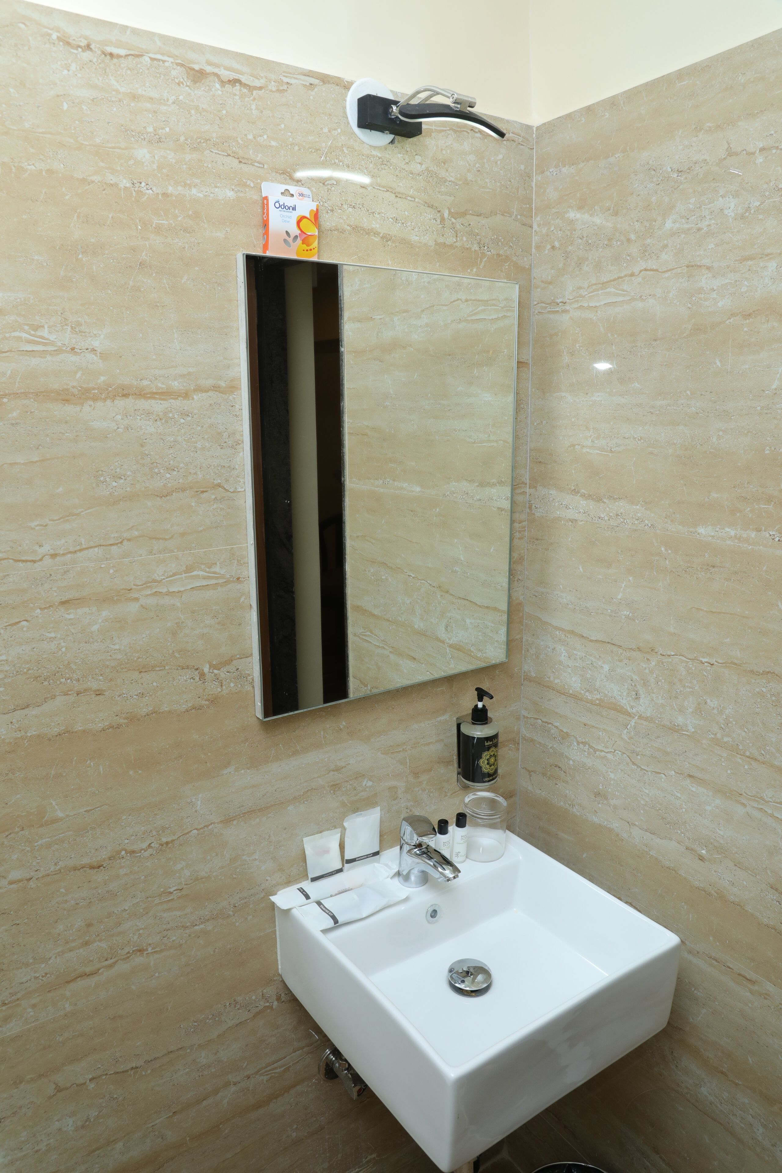 A bathroom with a white sink, a mirror, and a towel dispenser.