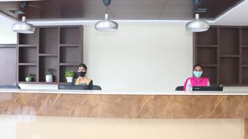 A reception desk with two staff members, a marble counter, and pendant lighting.